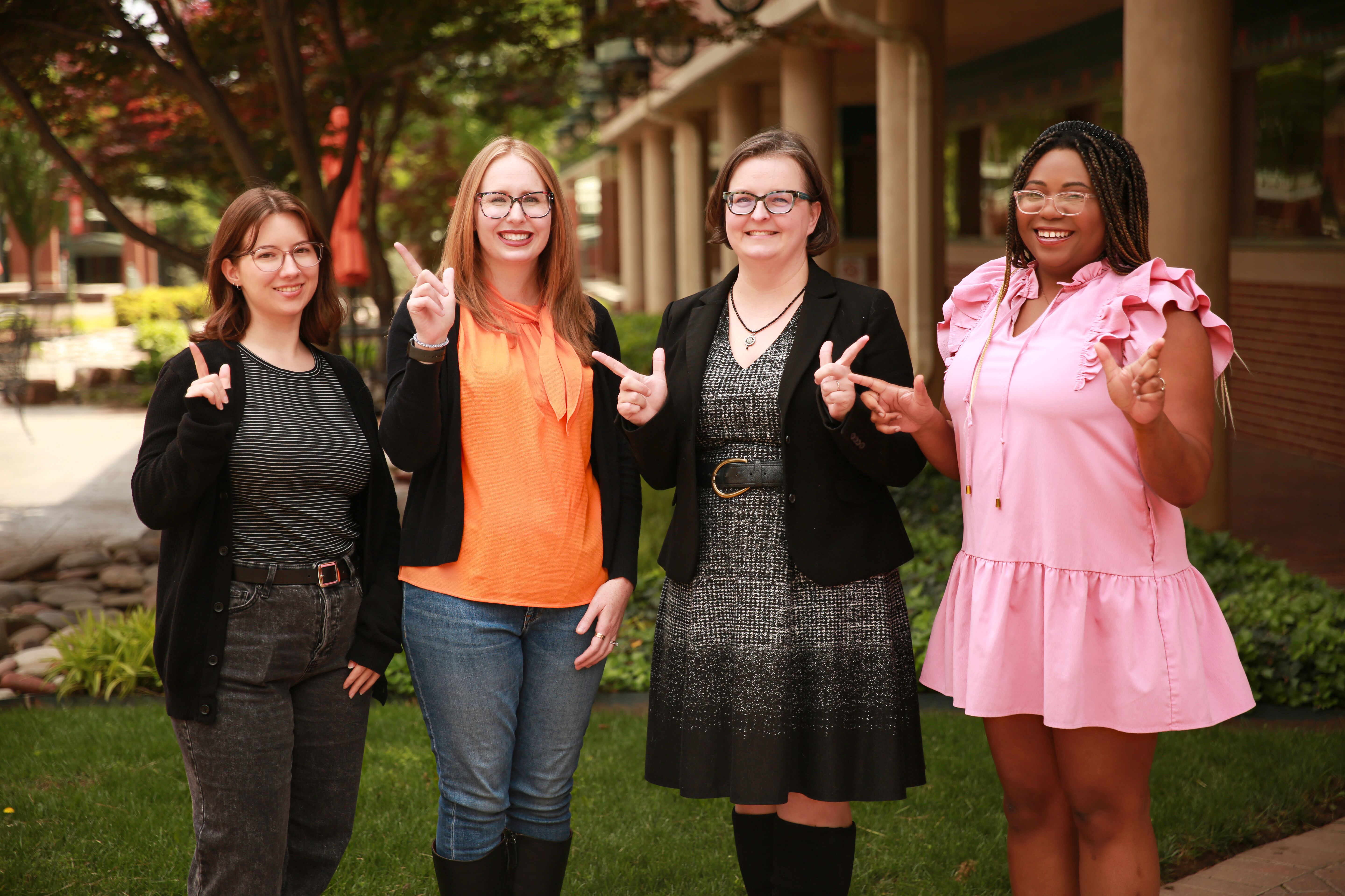 Group of four people stand outside smiling.
