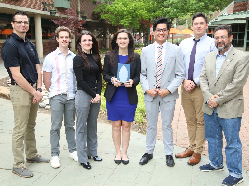 ASME Members stand in the courtyard while holding their award.