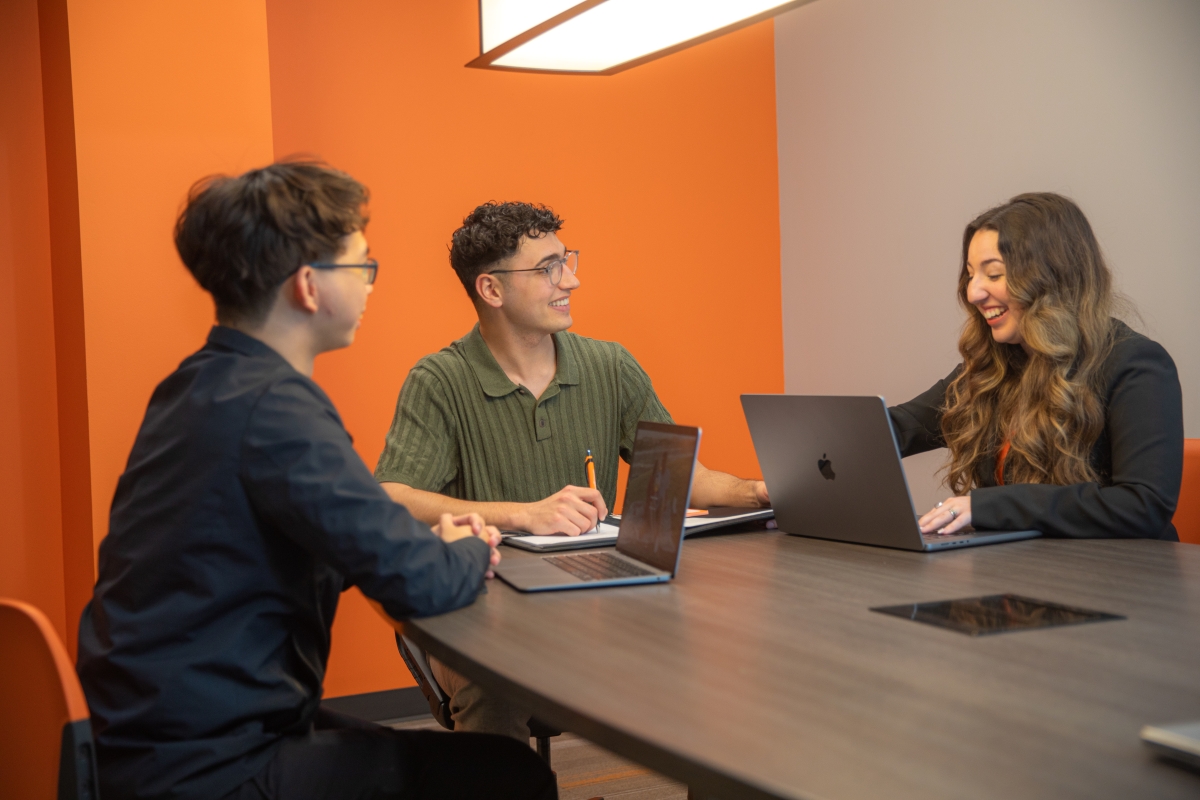 Three people sitting and reviewing items on computer screen