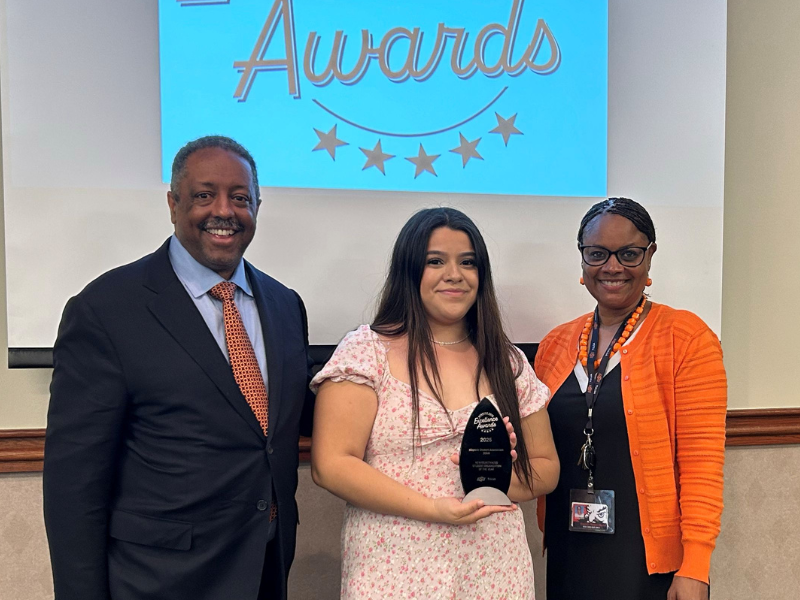 Student stands holding award.